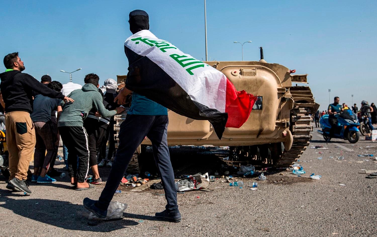 Iraqi protesters gather outside an abandoned army armoured personnel carrier at a demonstration outside the southern port of Umm Qasr, on November 5, 2019. Photo: Hussein Faleh/AFP