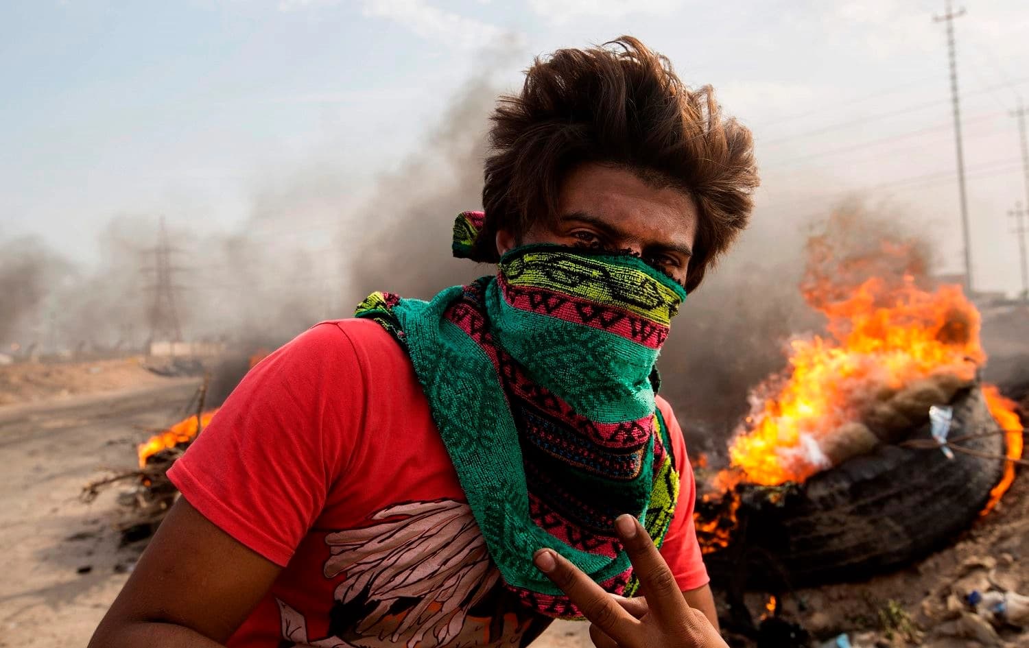 An Iraqi protester walks past burning tires as others block the road to Umm Qasr port during ongoing anti-government demonstrations in southern Iraq on November 7, 2019.Photo: Hussein Faleh/AFP