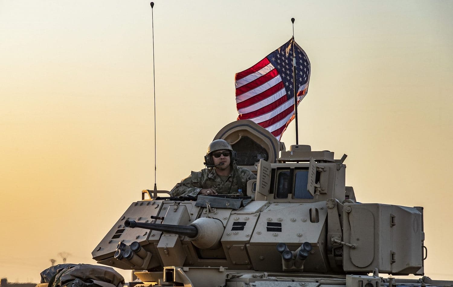 A US soldier sits atop a Bradley armoured personnel carrier as it drives near the town of Tal Tamr in the northeastern Syrian Hasaka province on the border with Turkey, on November 10, 2019. Photo: AFP / Delil Souleiman