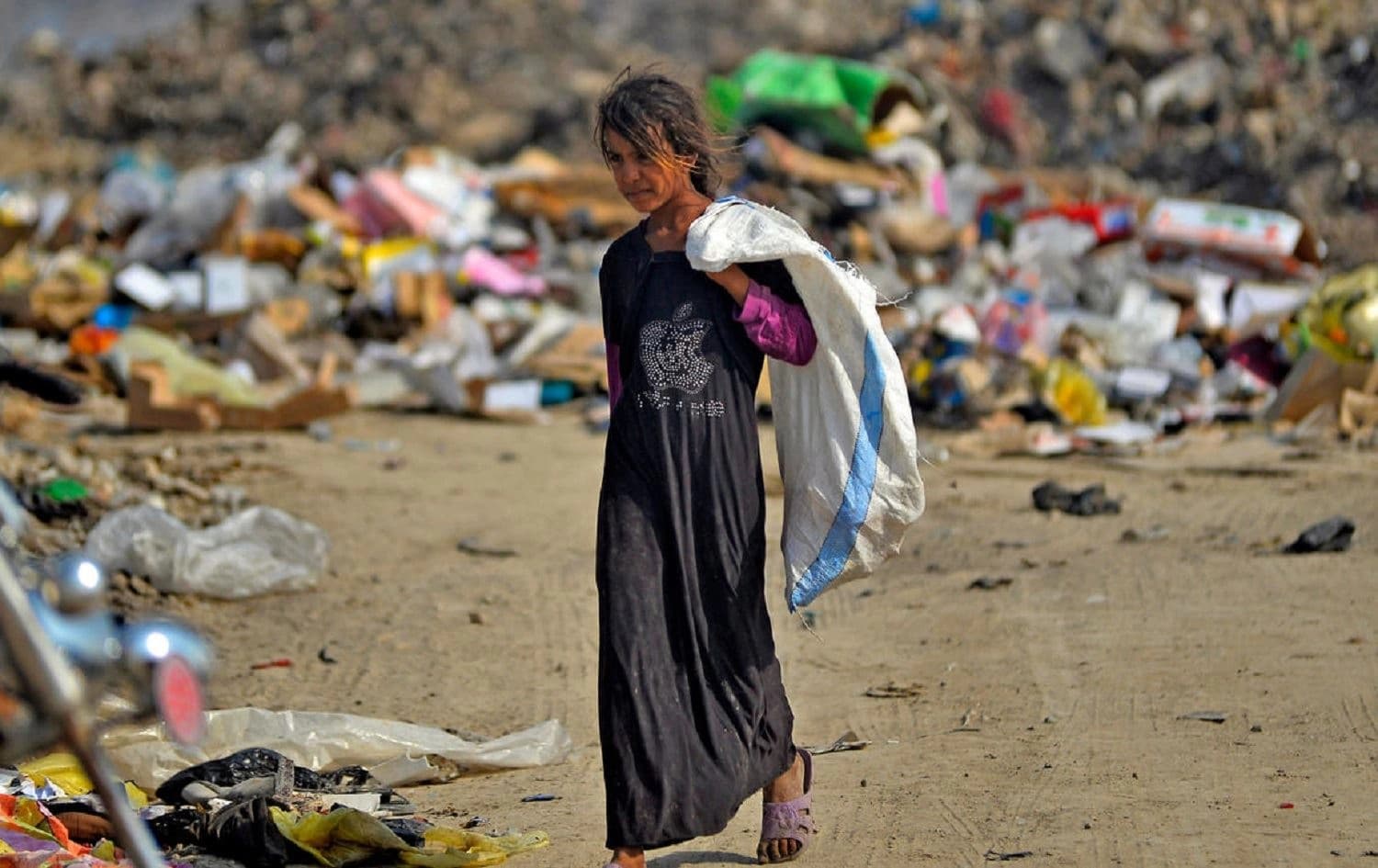 An Iraqi girl carrying a bag walks amidst piles of rubbish in a landfill in Diwaniya, south of the capital Baghdad. Photo: Haidar Hamdani / AFP