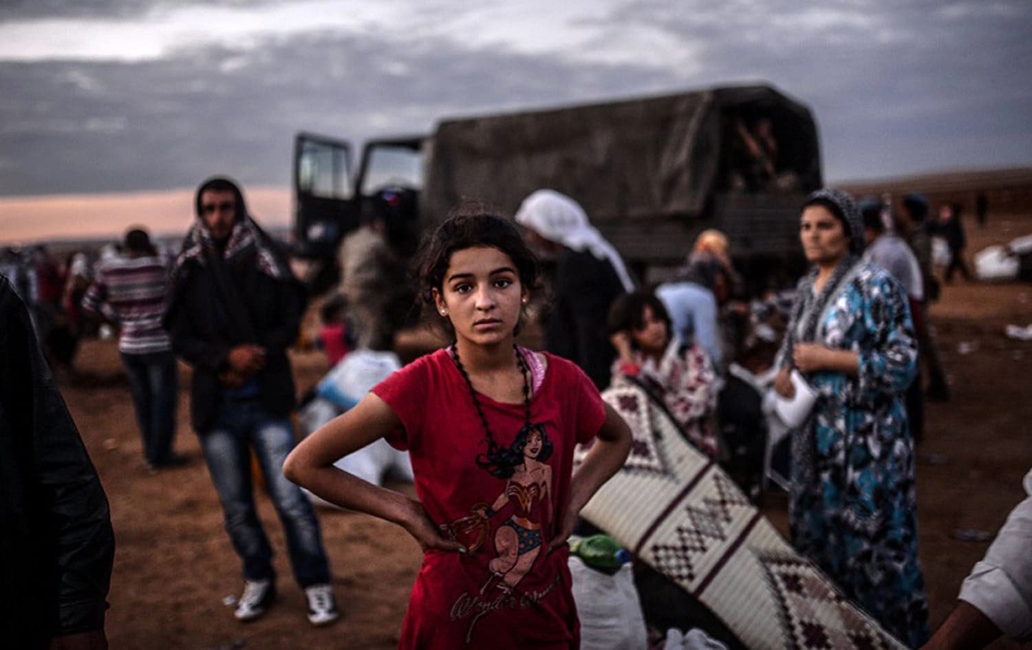 Syrian Kurds wait as they cross the border between Syria and Turkey. Photo via AFP / Bulent Kilic