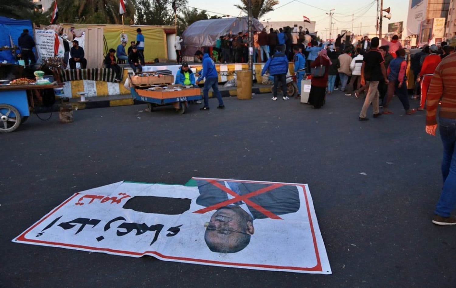A poster with a defaced photo of Qusay al-Suhail, a candidate for prime minister lies on the ground in Tahrir Square, Baghdad, Iraq. Photo: Khalid Mohammed / AP