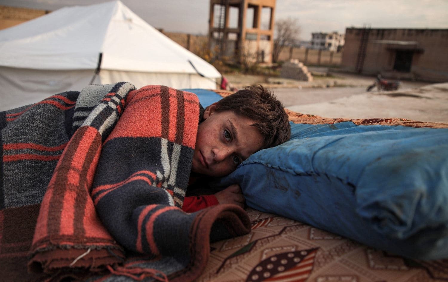 A Syrian child sleeps on a futon in the open at a camp for the displaced near the town of Dana, northern Idlib province on December 27, 2019. Photo: Aaref Watad / AFP