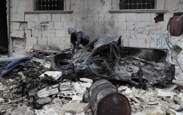 A man perches on a destroyed vehicle amid rubble scattered across a street following a reported regime air strike in the town of Ariha in the Idlib province on January 5, 2020, killing at least 5 civilians. Photo: Omar Haj Kadour/AFP