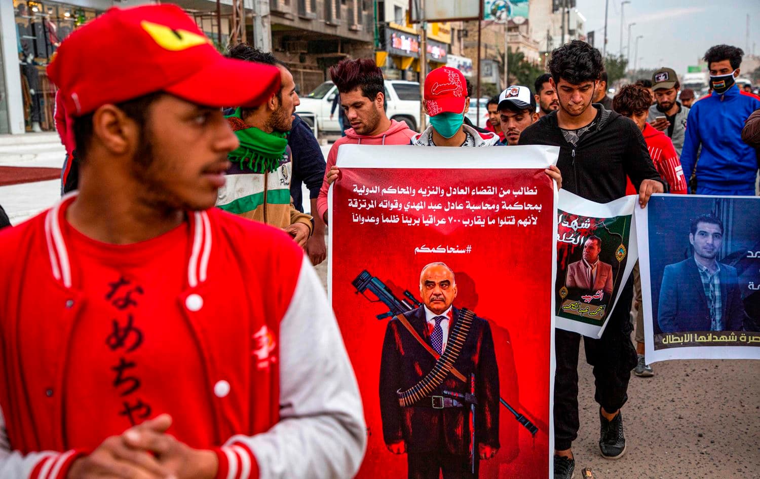 'We demand the fair and honest judiciary and the international courts to try and hold accountable Mr. Adil Abdul-Mahdi and his mercenary forces for unjustly killing almost 700 innocent Iraqis,' reads a banner depicting the prime minister as a sniper at a protest in Basra on January 17, 2020. Photo: Hussein Faleh/AFP