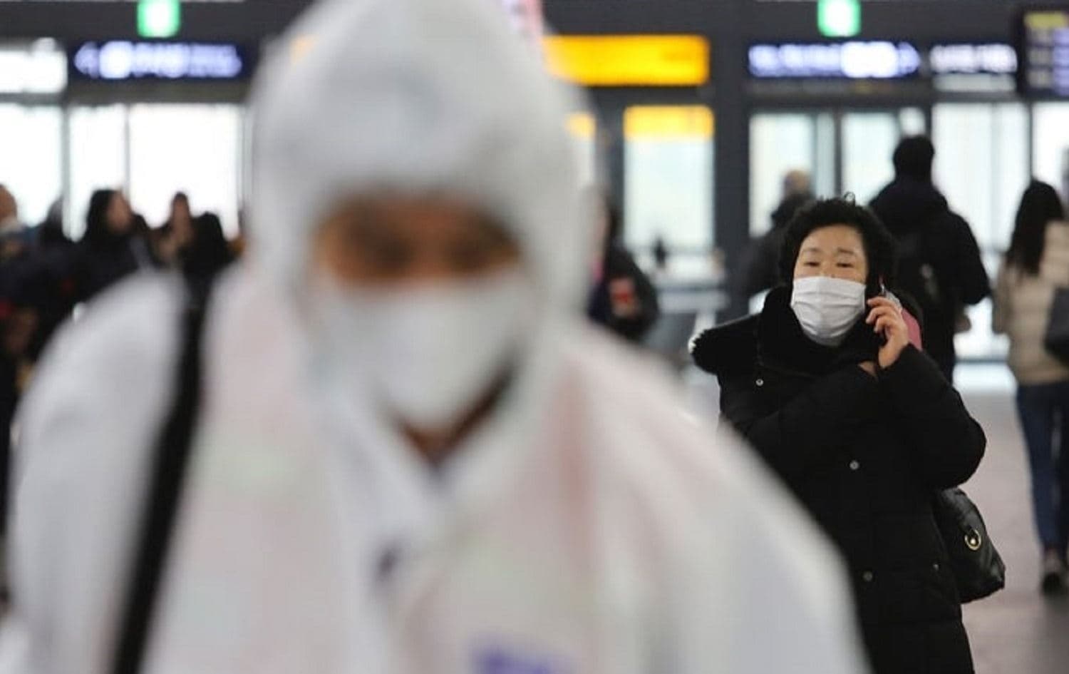 A woman wears a mask as an employee works to prevent the spread of coronavirus at Suseo Station in Seoul, South Korea, on January 24, 2020. Photo: Ahn Young-joon / AP