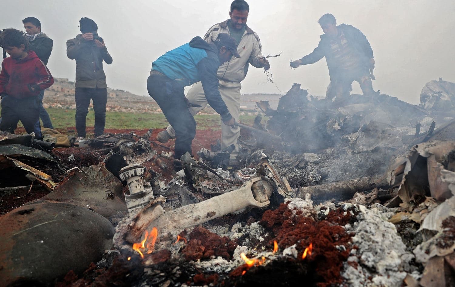 People search for scraps of metal among the debris of a Syrian military helicopter shot down on February 14, 2020 in the western countryside of Aleppo province. Photo: Omar Haj Kadour / AFP