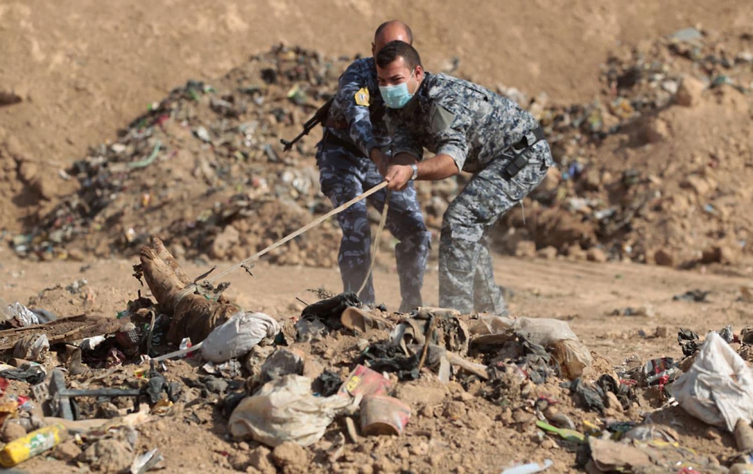 Members of the Iraqi security forces inspect a mass grave discovered in territory recaptured from the Islamic State group (ISIS) in 2016. File photo: AFP 