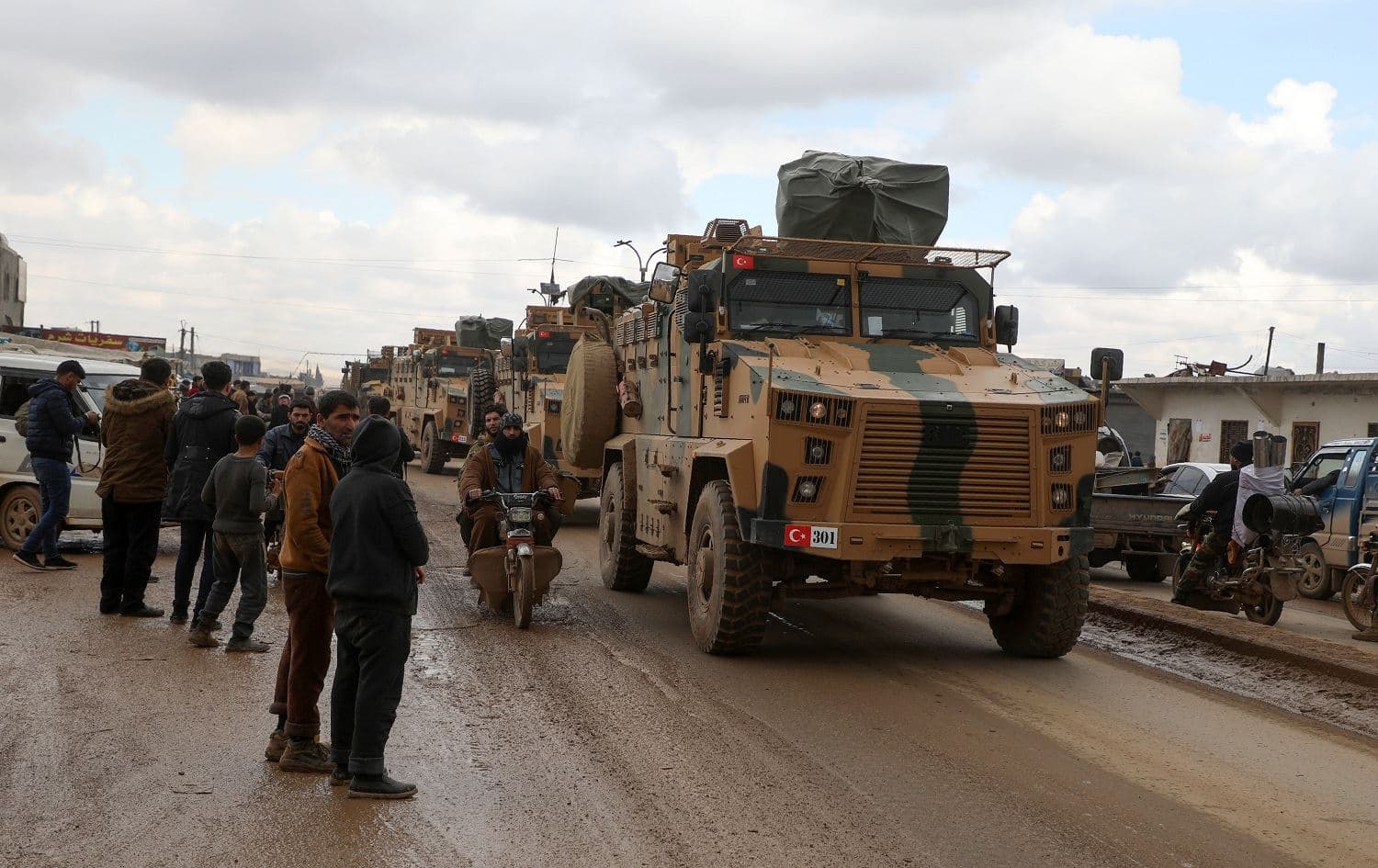 Residents watch as a Turkish military convoy passes through the Syrian rebel-held town of Hazano in Idlib's northern countryside on February 22, 2020. Photo: Aaref Watad / AFP