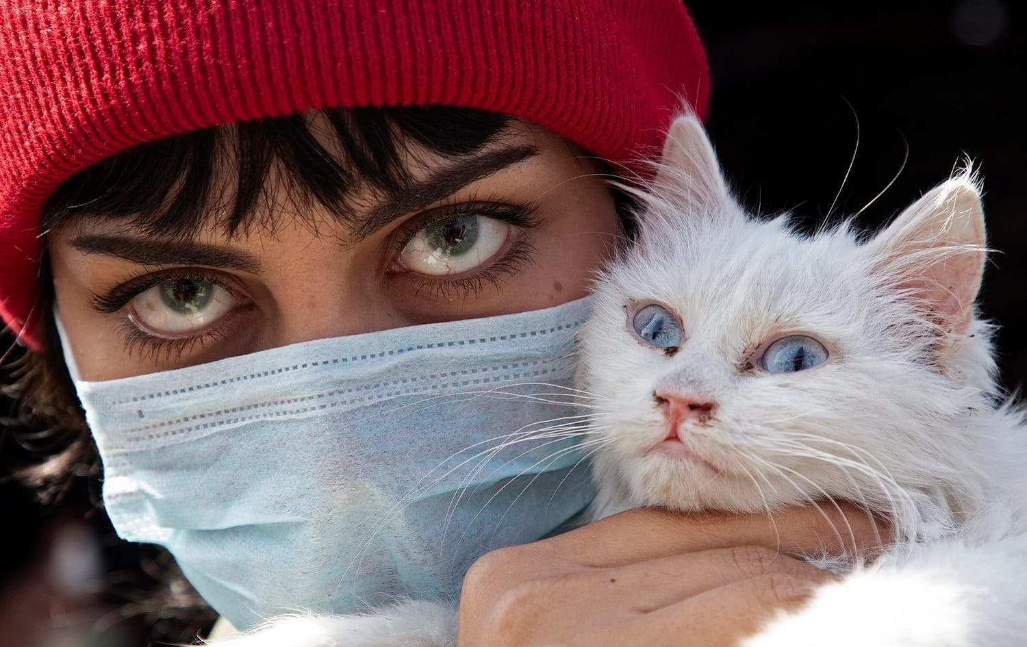 An Iraqi woman wearing a protective mask holds her cat as she poses for a picture during a protest against corruption in the Iraqi government in the southern city of Basra, February 27, 2020. Photo: Hussein Faleh / AFP