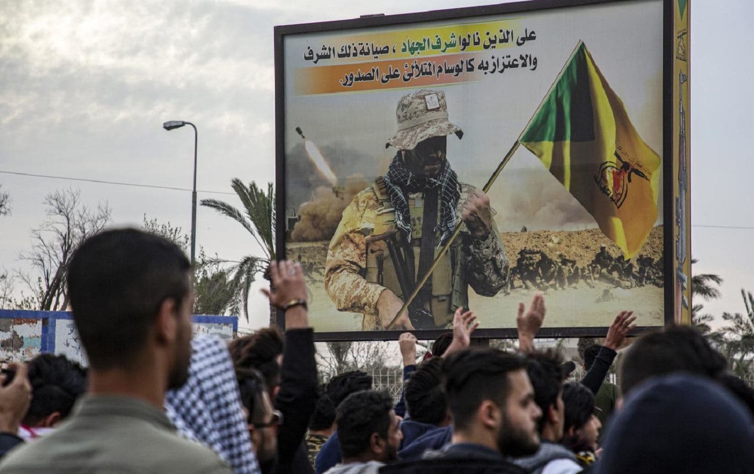 Protesters chant slogans as they walk past a Kataib Hezbollah billboard during an anti-government demonstration in Basra. File photo: AFP