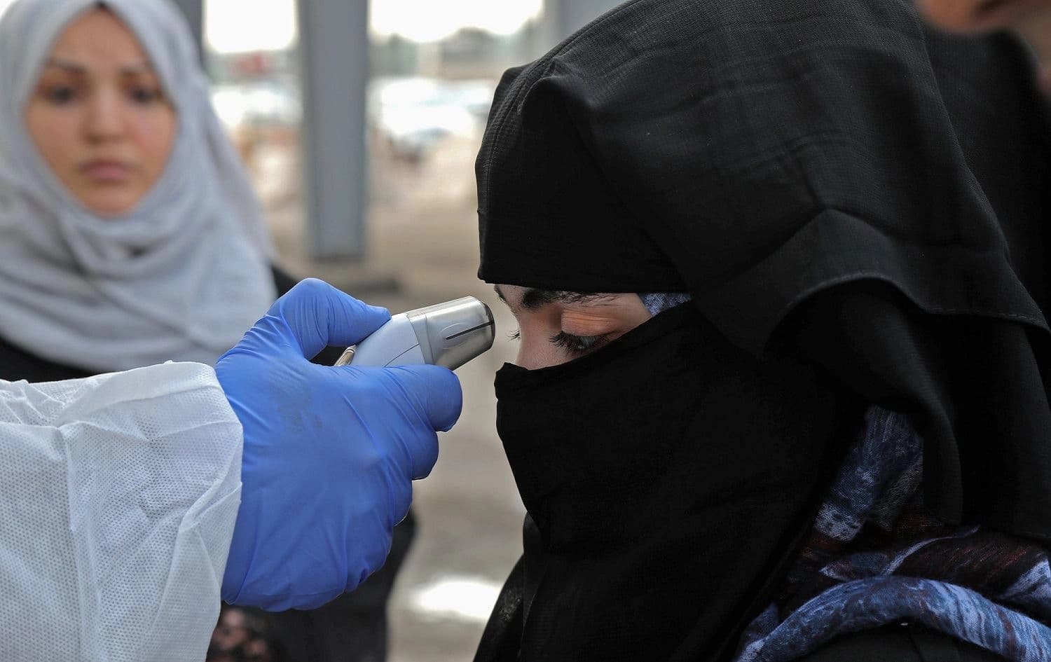 A medic checks the body temperature of a woman arriving at an Erbil checkpoint, March 2, 2020. Photo: Safin Hamed / AFP 