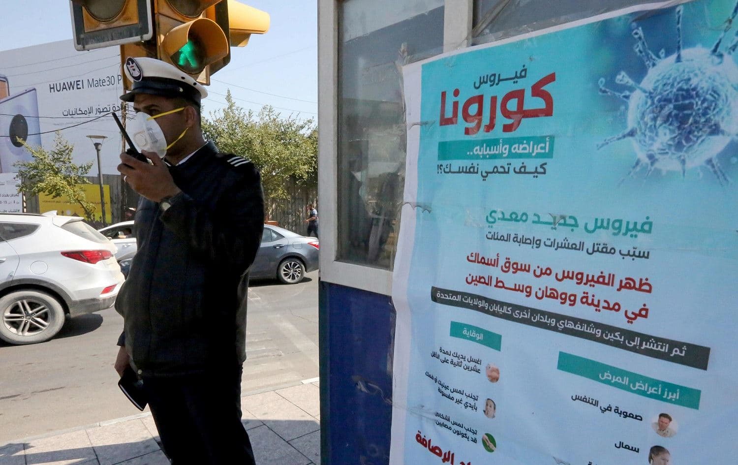 A policeman wearing a protective mask stands next to a coronavirus information poster in Baghdad's Karrada neighbourhood, March 10, 2020. Photo: Sabah Arar / AFP