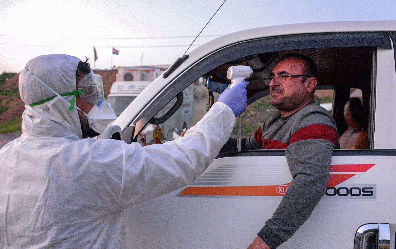 An Iraqi health ministry worker scans the body temperature of a driver of an incoming vehicle in Iraq's northern city of Mosul, March 8, 2020. Photo: Zaid al-Obeidi / AFP