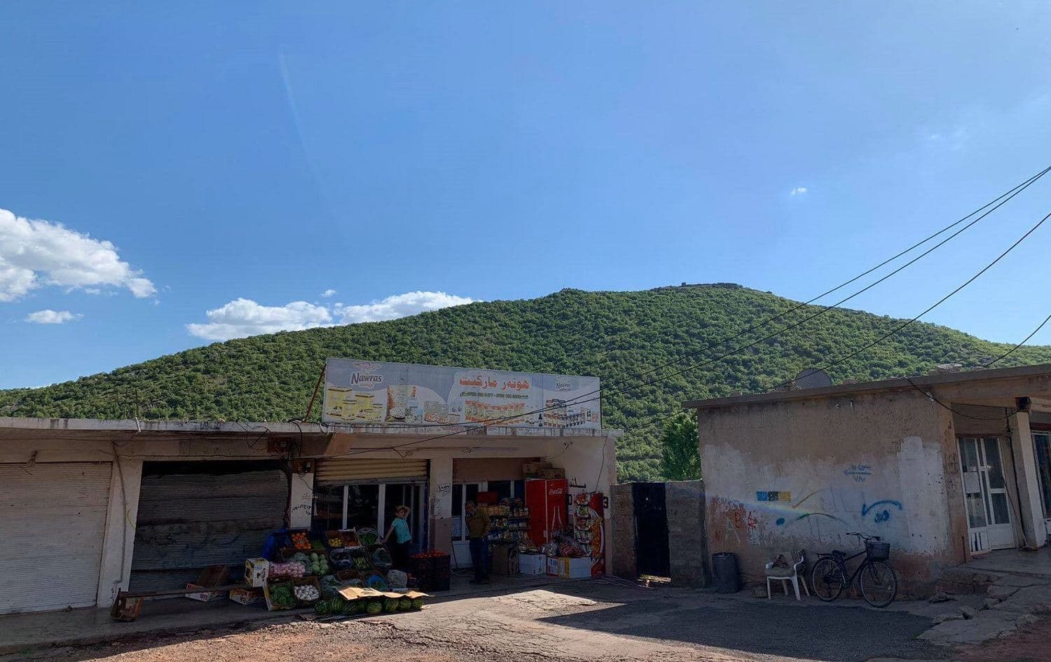 A shop in the town of Kani Masi, with its Turkish military base in view atop the mountain. Photo: Naif Ramadan / Rudaw