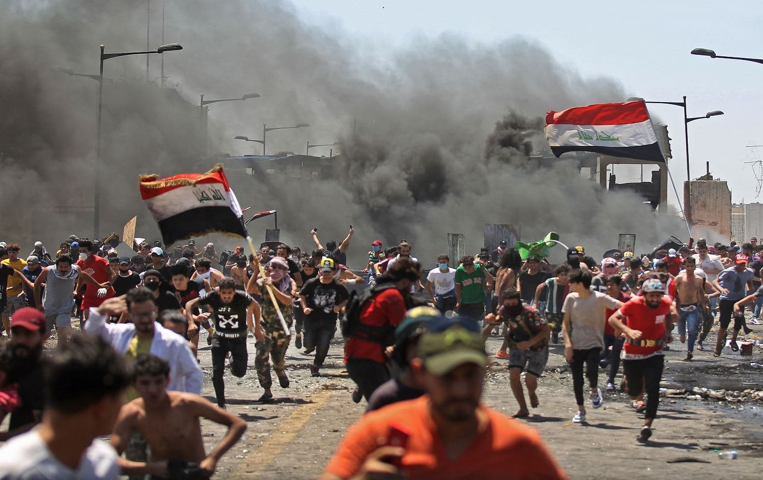 Iraqi protesters run for cover as they clash with security forces on Al-Jumhuriyah bridge, Baghdad, during an anti-government demonstration on May 10, 2020. Photo: Ahmad al-Rubaye/AFP