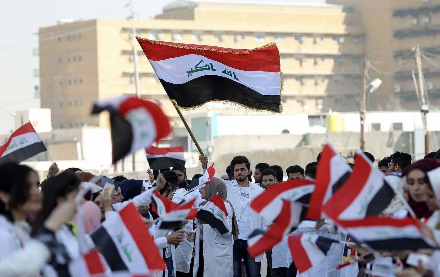 Iraqi medical students wave the national flag as they take part in an anti-government protest at the University of Basra on November 12, 2019. File photo: Hussein Faleh/AFP 