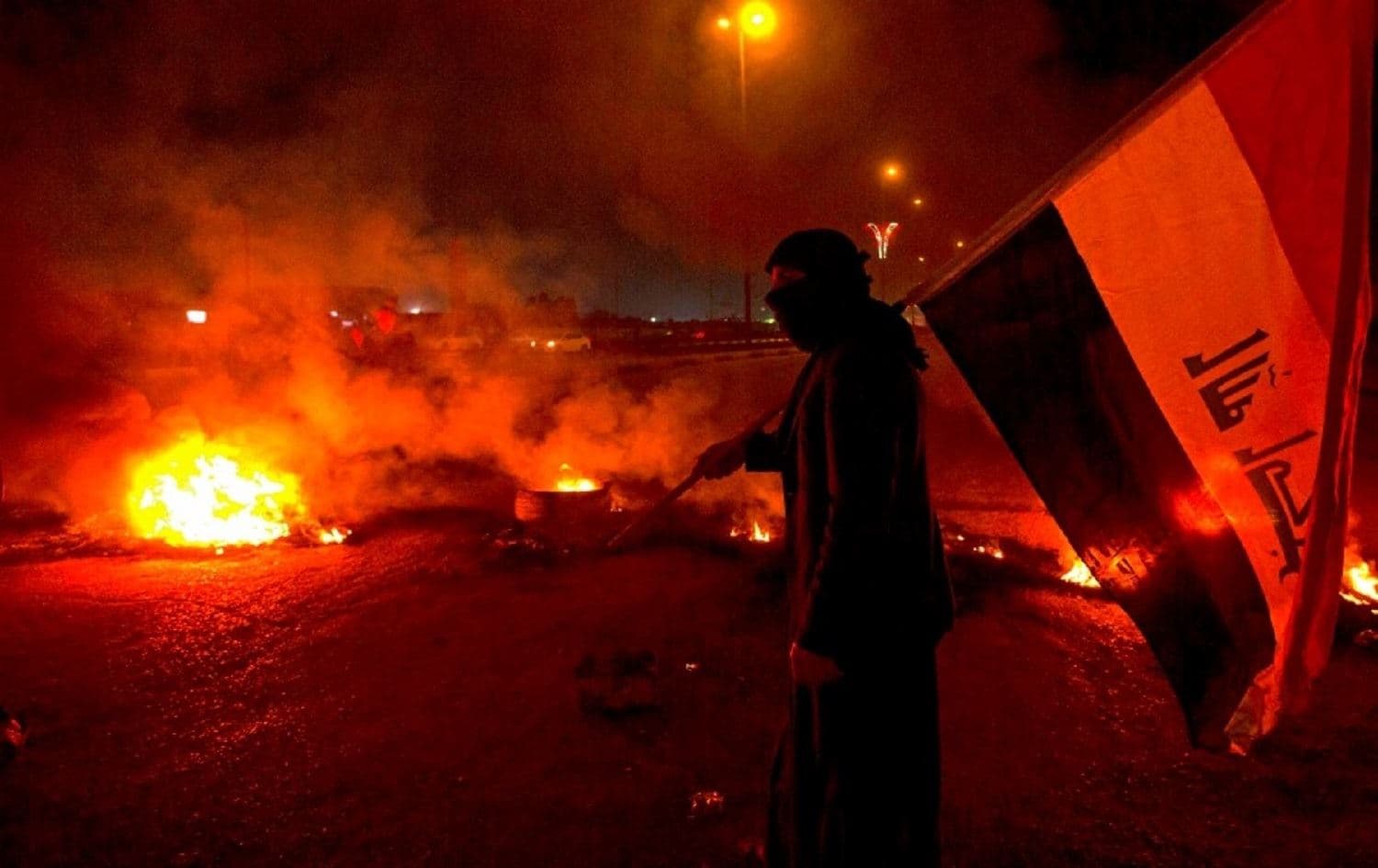 An Iraqi protester holds the national flag at a roadblock in the southern Iraqi city of Basra on December 23, 2019. File photo: AFP