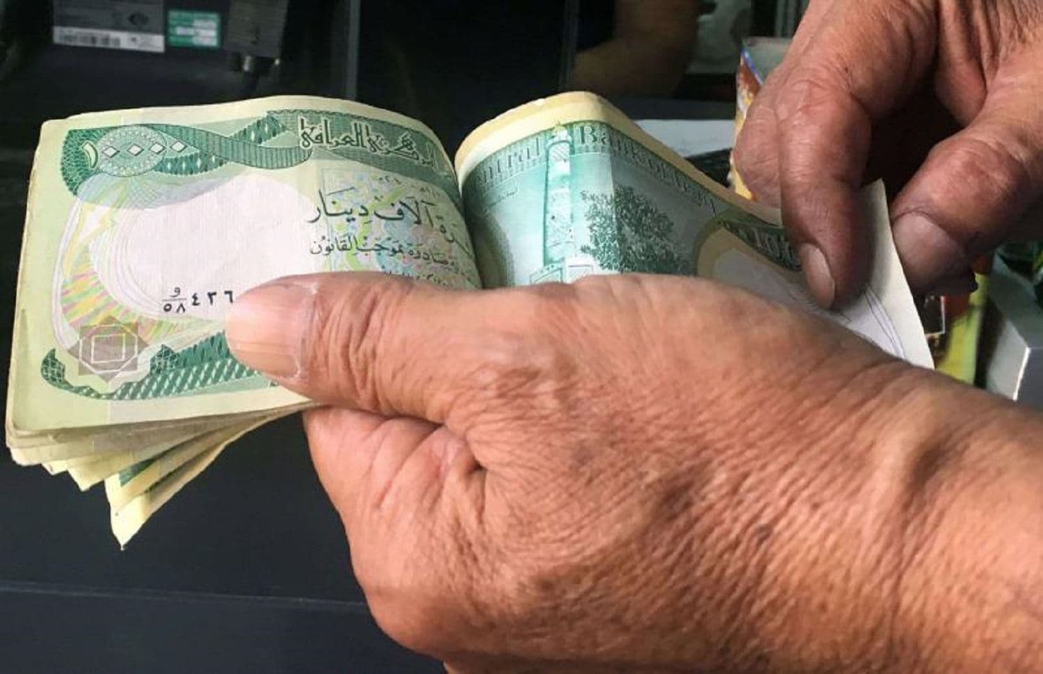 An Iraqi customer pays with Iraqi dinar banknotes in the capital Baghdad. Photo: AFP