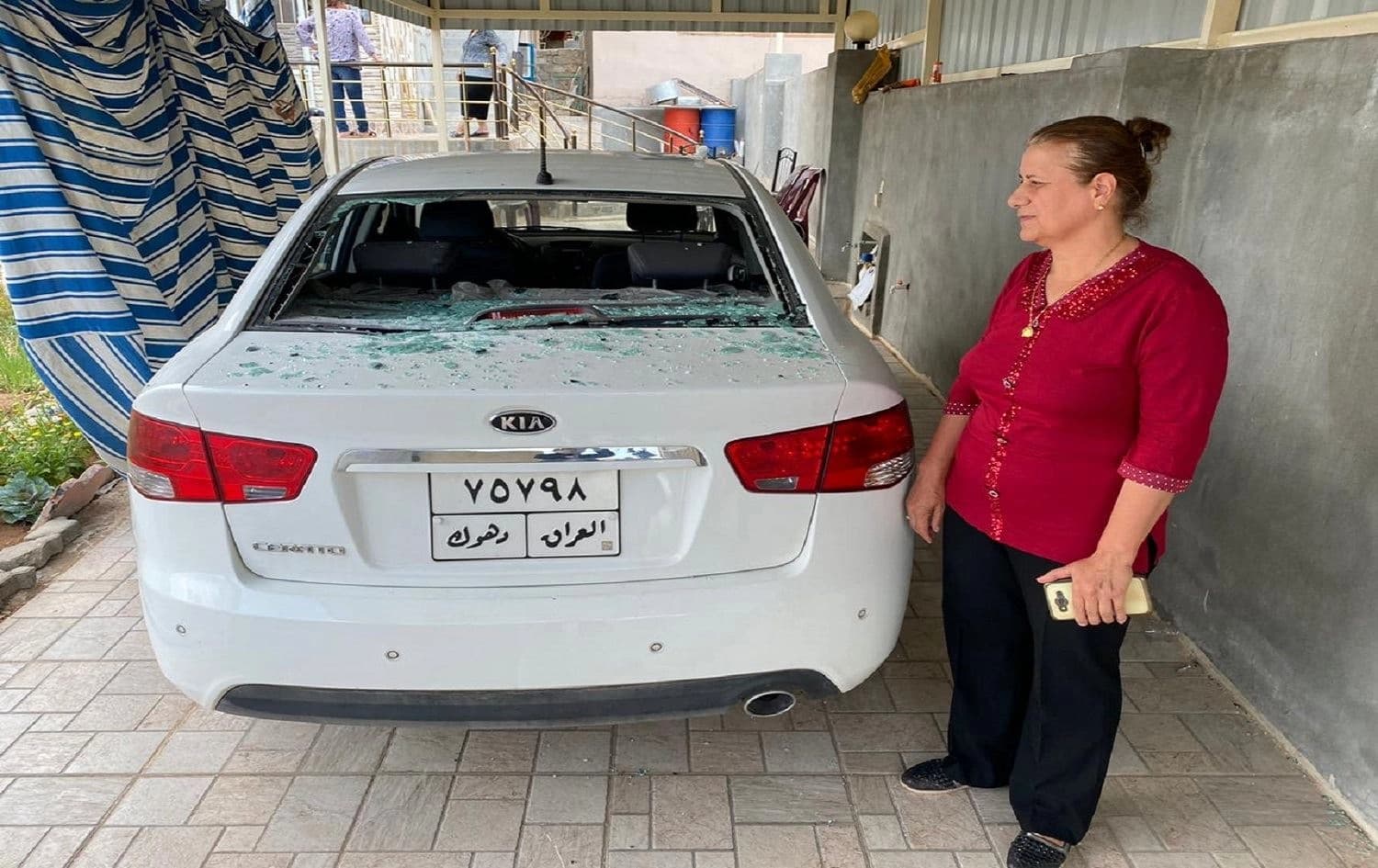 Faiza Rahim, a Christian teacher from Duhok province, stands next to her car's windshield, which she says was smashed during a Turkish bombing Saturday. Photo: Rudaw/Yousif Musa