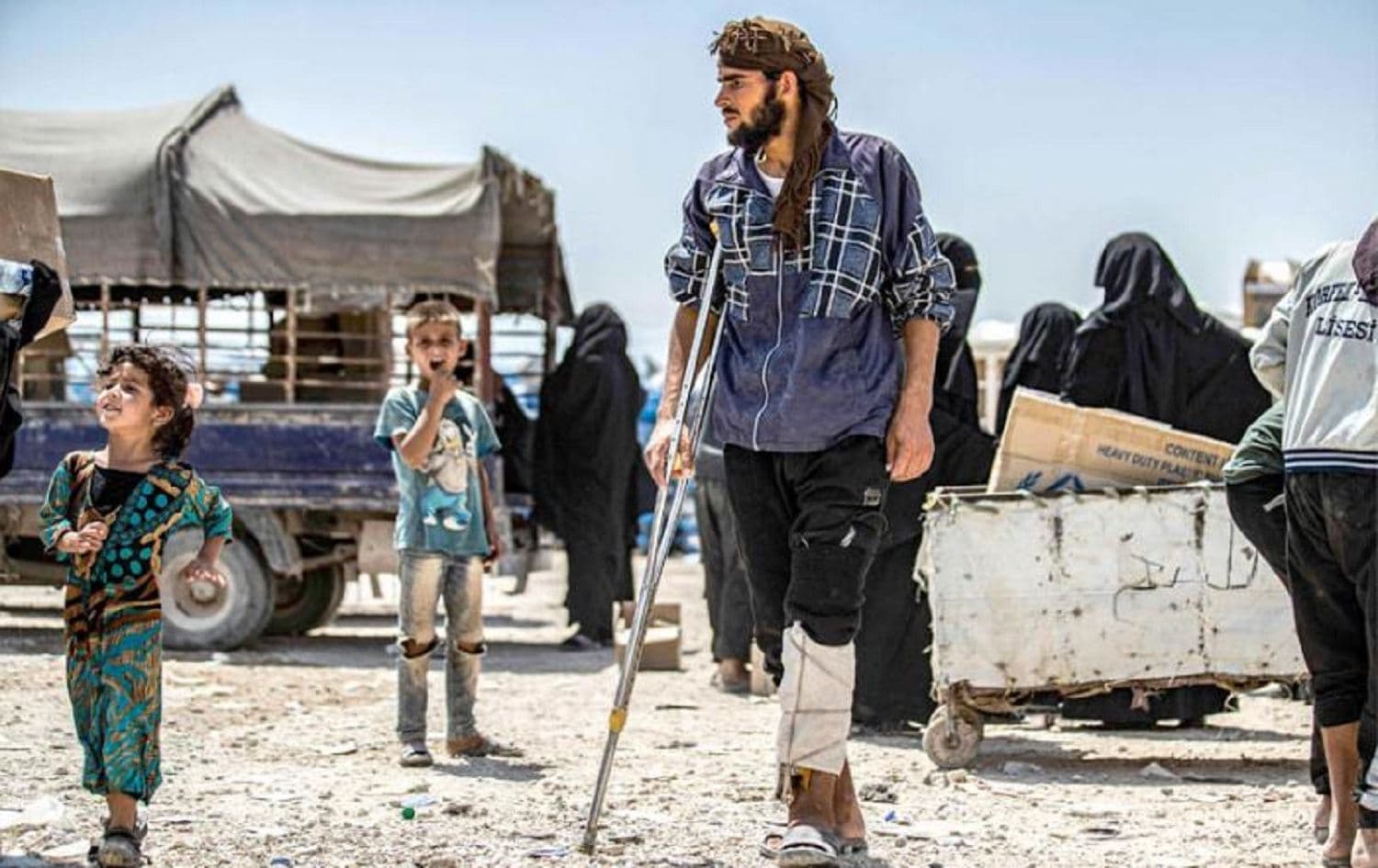 An ISIS suspect with an injured leg walks on crutches alonside children at al-Hol camp in Hasaka, northeast Syria in July 2019. Photo: AFP 