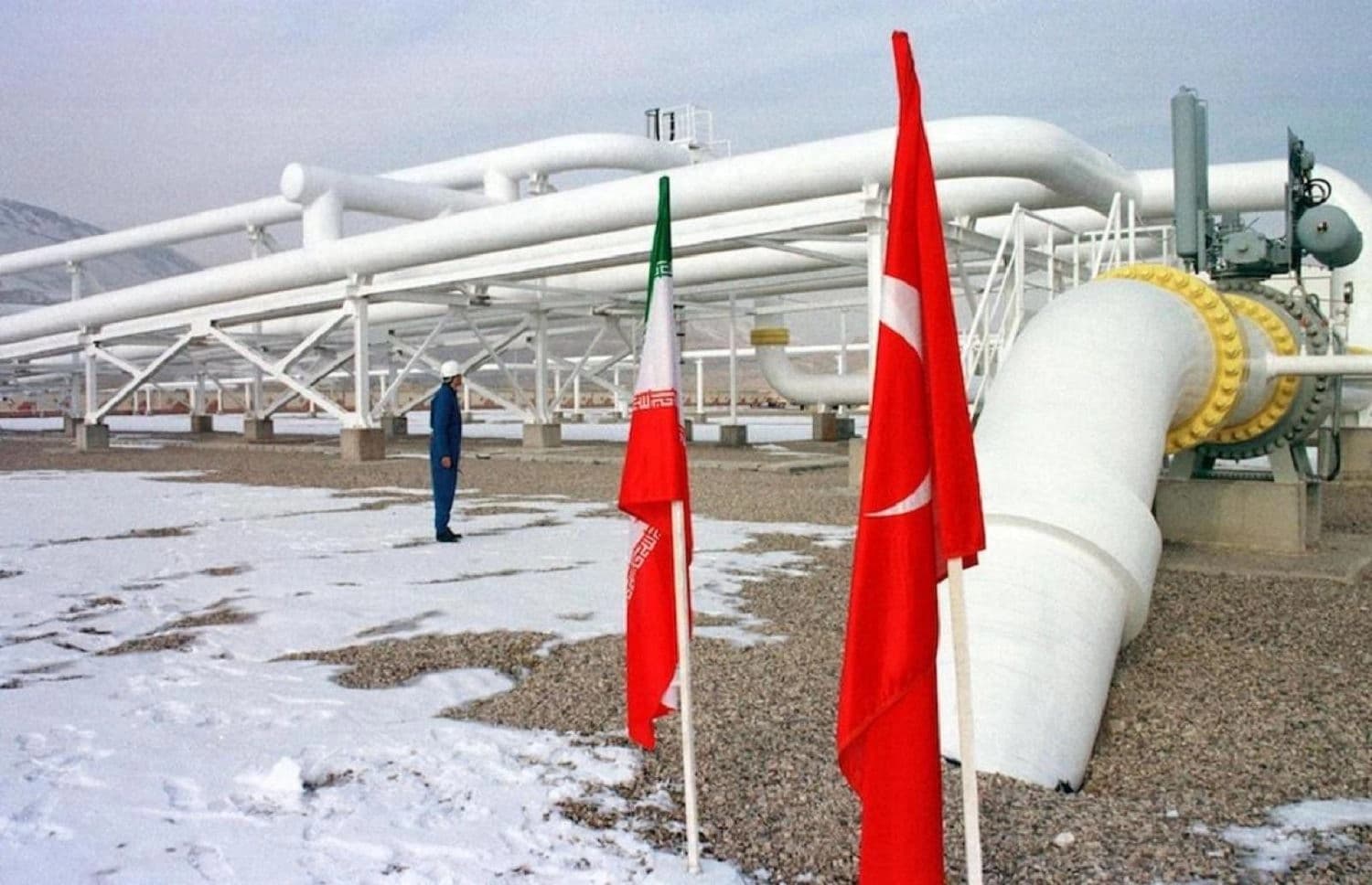 Iranian worker stands in front of gas pipelines next to flags of Turkey and Iran. Photo: AFP
