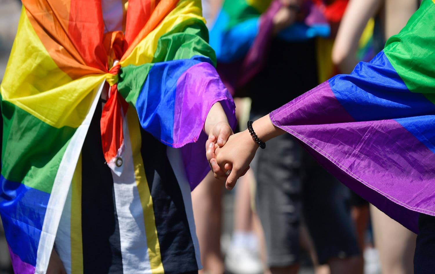 People wearing rainbow flags hold hands as they take part in a Pride March in Berlin on June 27, 2020. Tobias Schwarz / AFP