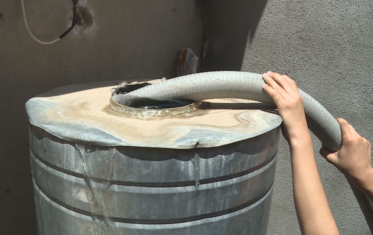 Somebody fills their household's rooftop tanker with water bought in Erbil's Adala neighborhood. Photo: Rudaw video