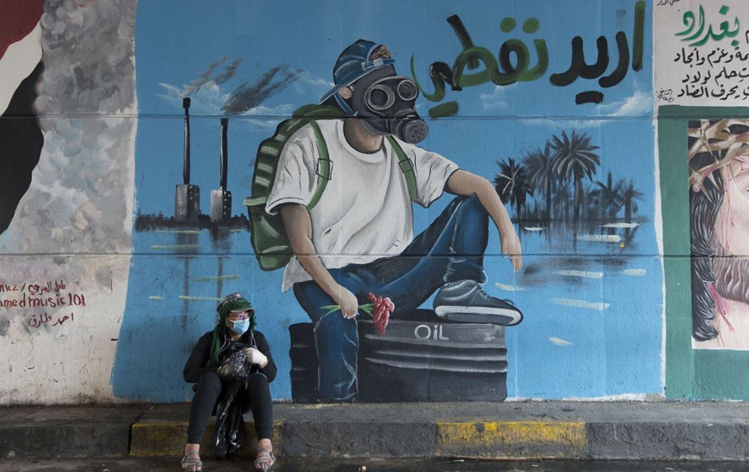 A protester sits by a mural that reads "I want my oil" in Baghdad, Iraq on December 8, 2019. File photo: Nasser Nasser/AP