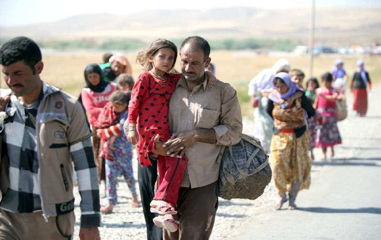 A displaced Iraqi man from the Yazidi community carries his daughter as they cross the Iraqi-Syrian border. Photo: Ahmad al-Rubaye/ AFP