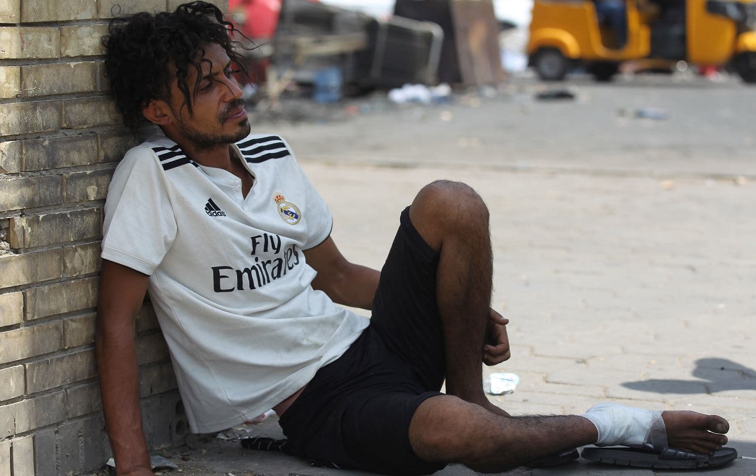 An Iraqi protester wounded the previous night in confrontations with security forces sits on July 27, 2020 on the ground in Baghdad's Tahrir square, where several protest tents were burnt the previous night. Photo: Ahmad al-Rubaye / AFP