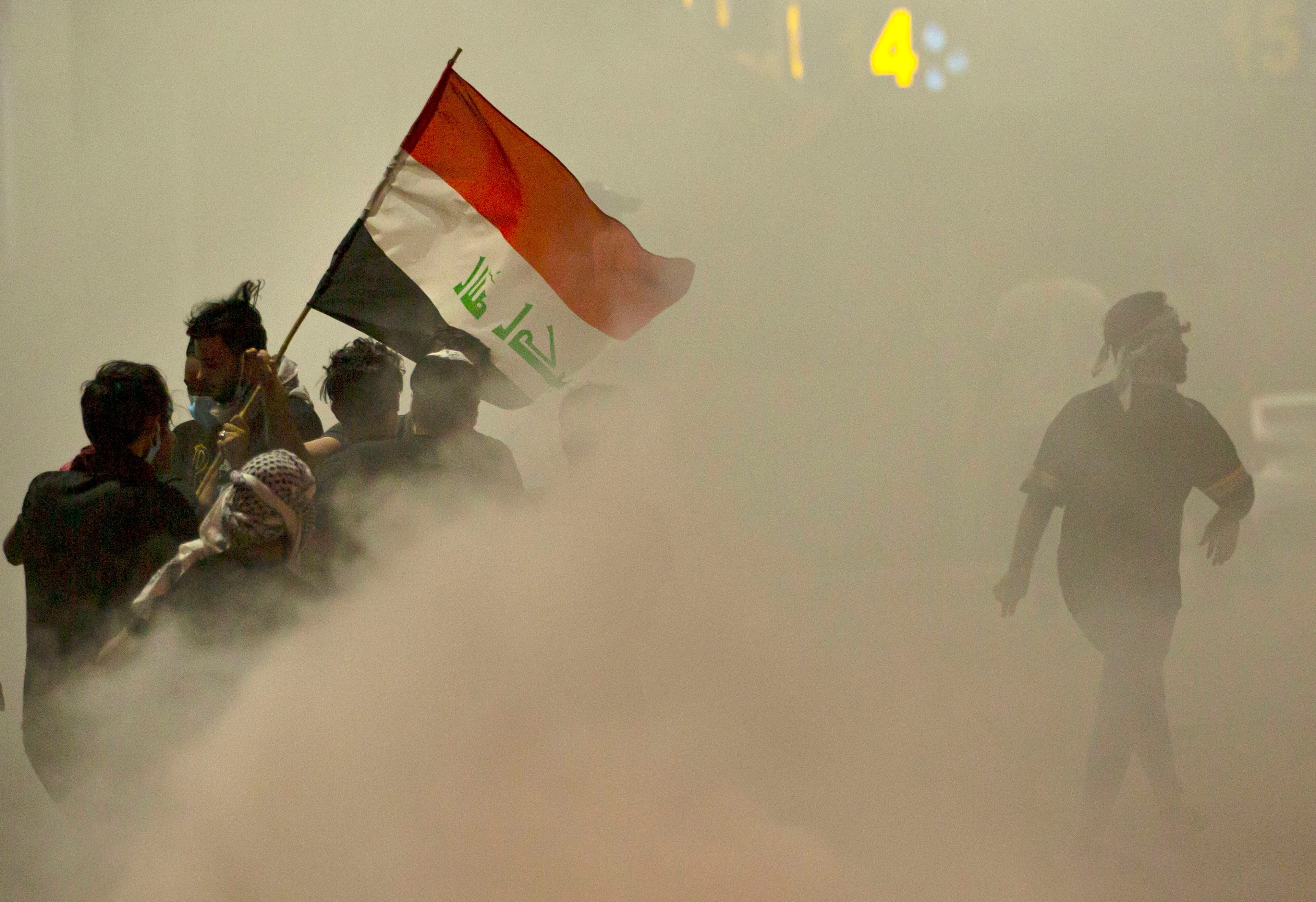 Iraqi demonstrators gather amid smoke after fire services extinguished fire on tires during a protest near the governor's residence in the southern city of Basra, to oppose assassinations and demand the resignation of top security officials in the southern Iraqi governorate, on August 17, 2020. Photo: Hussein Faleh / AFP