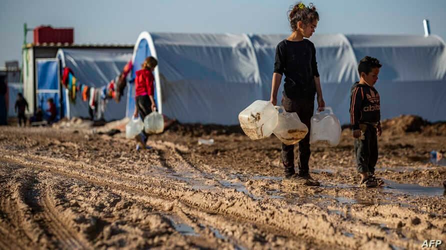 Children carry jugs to fill with water at Washukanni camp on the outskirts of Hasaka, northeastern Syria on December 16, 2019. Photo: Delil Souleiman / AFP