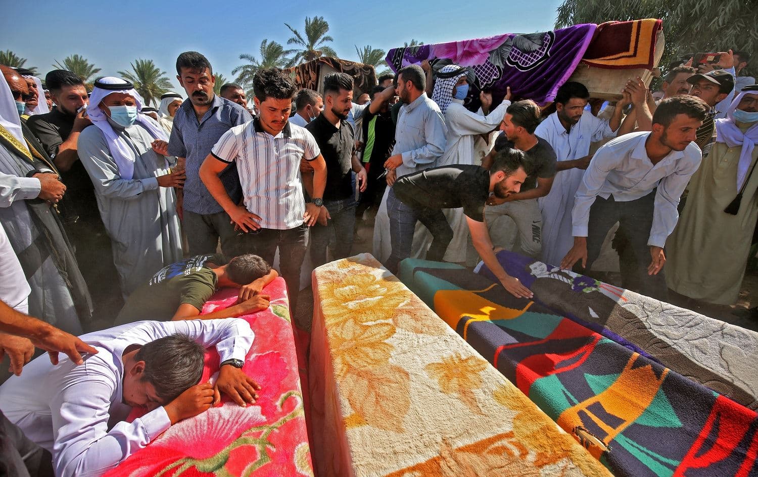 Iraqi men mourn over the coffins of members of a family who were killed a day earlier when a rocket hit their home near Baghdad's airport. Photo: Ahmad al-Rubaye / AFP