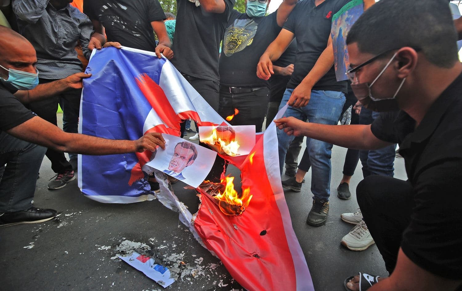 Iraqi protestors burn posters and the French flag during a demonstration against French President Emmanuel Macron in front of the French embassy in Baghdad on October 26, 2020. Photo: Ahmad al Rubaye/AFP