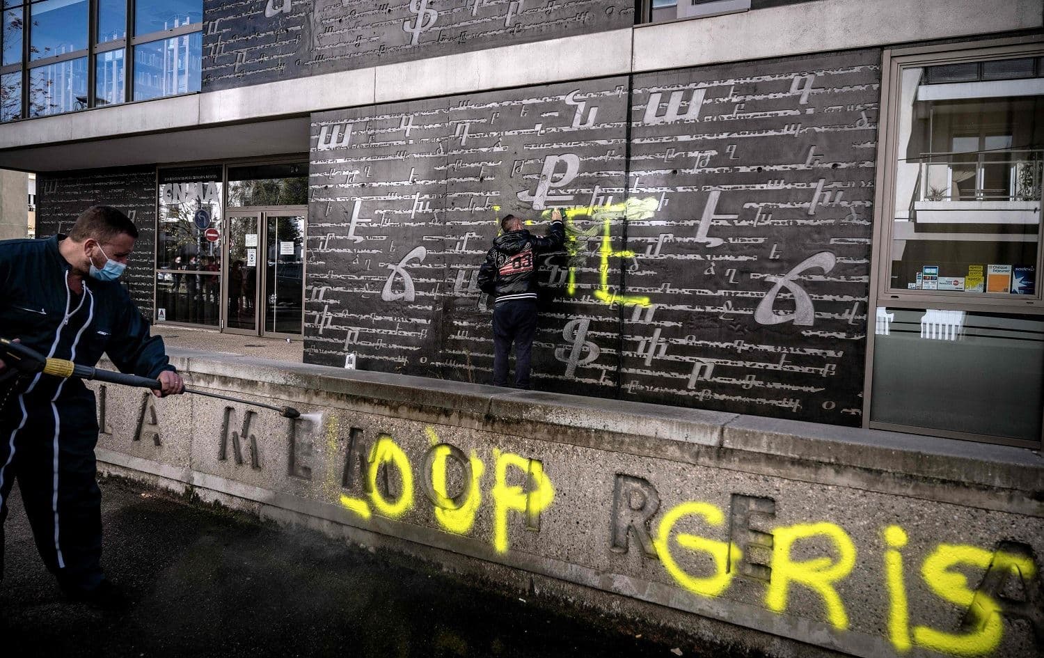 Men clean an outside wall of the National Armenian Memorial Centre in Decines-Charpieu, near Lyon, on November 1, 2020 where 'Loup Gris' [Grey Wolves] graffiti tags were painted overnight. Photo: Jeff Pachoud/AFP