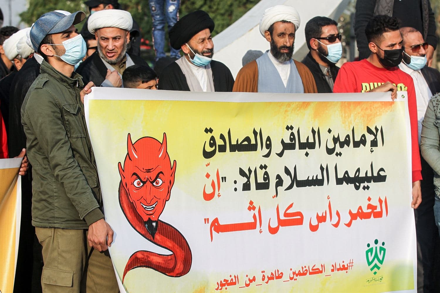 A group calling itself "Tajammu' Shabab al-Sharia" (Sharia Youth Rally) march with a banner quoting Shiite Imams Baqir and Sadiq as saying that alcohol is the root of all sin, during a demonstration in Iraq's capital Baghdad on December 3, 2020. Photo: Ahmad Al-Rubaye / AFP
