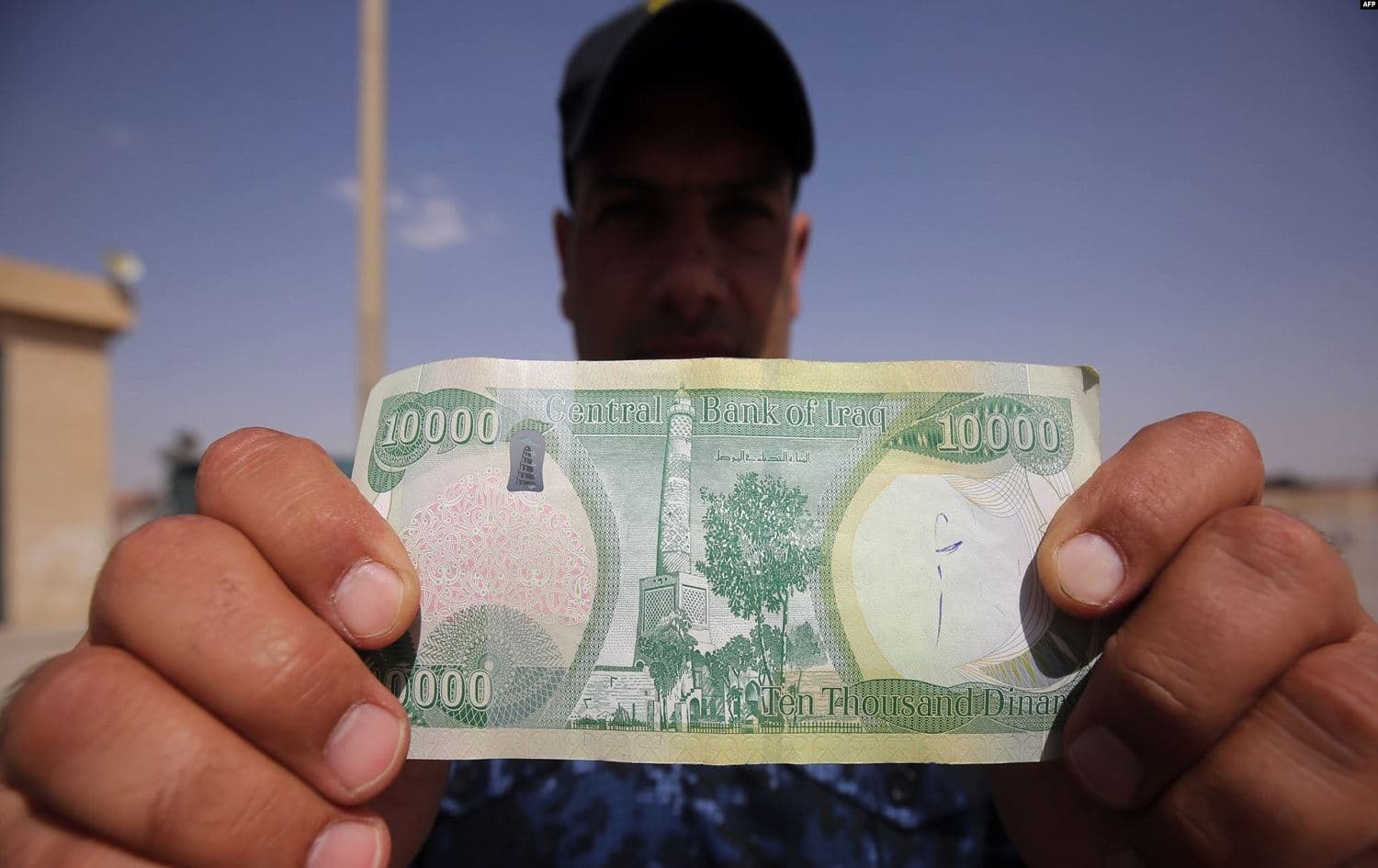 A man holds a 10,000-dinar note. File photo: AFP
