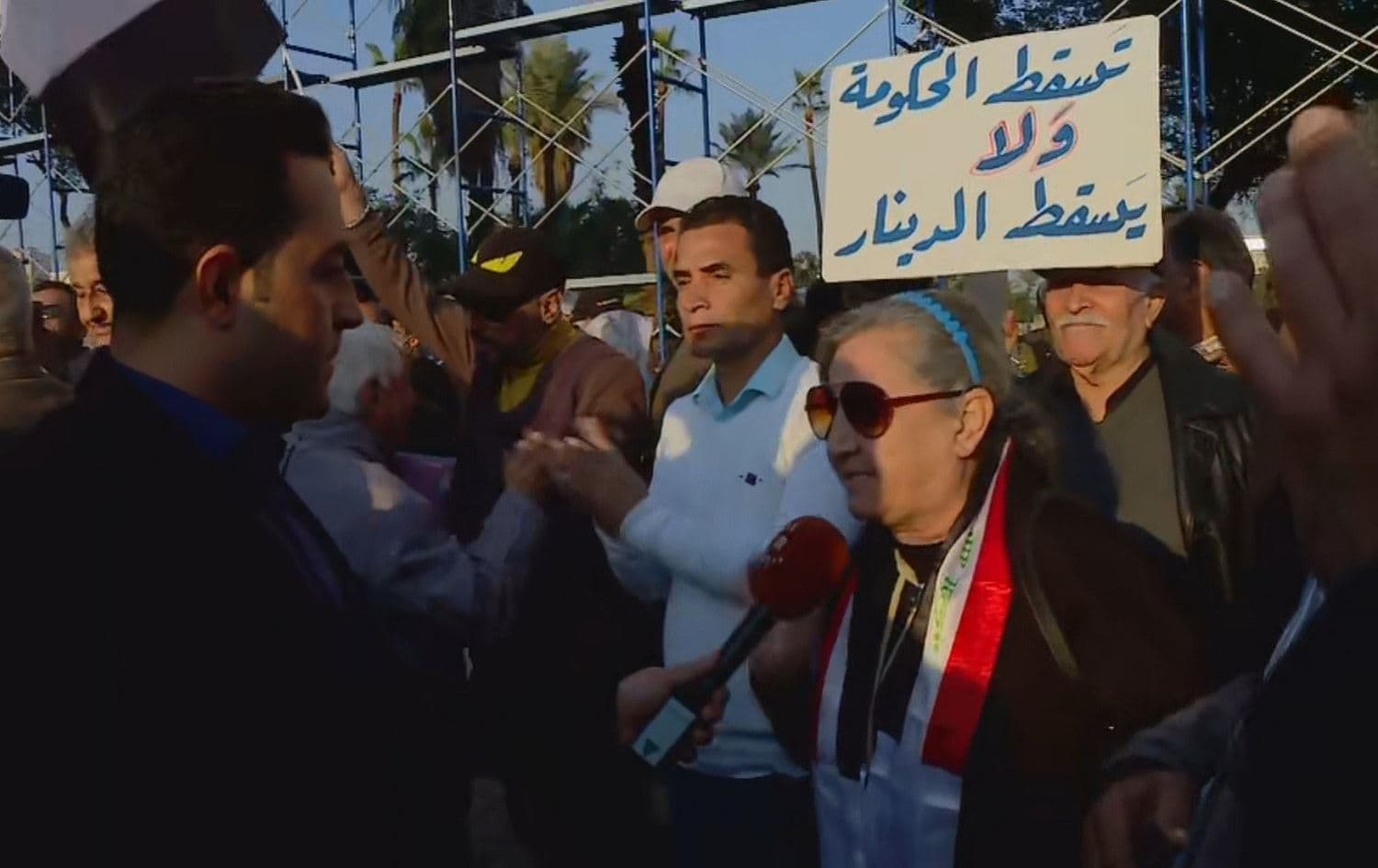 A protester in Tahrir Square carries a sign reading "Fall of the government, not fall of the dinar" on December 21, 2020. Photo: Rudaw