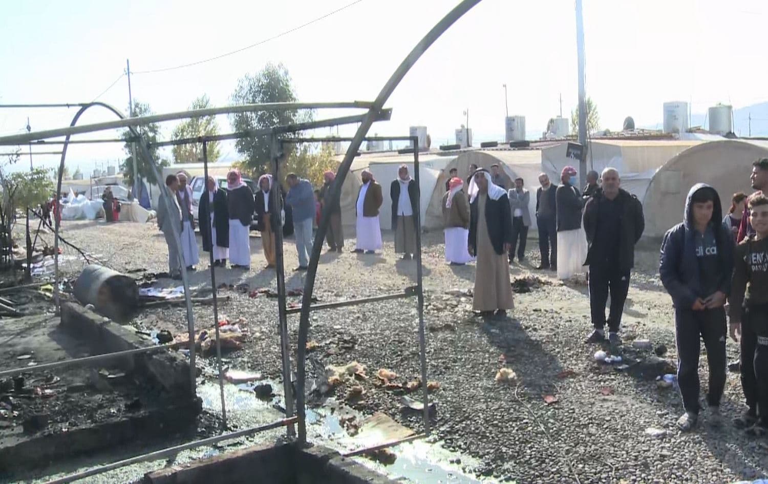 Residents of Chamshko camp look at the remains of tents that burned down overnight in a suspected electrical fire. Photo: Rudaw