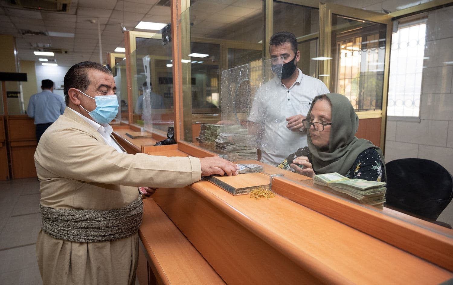 A man, wearing a mask during the coronavirus pandemic, collects a salary payment from an Erbil bank on August 19, 2020. File photo: Bilind T. Abdullah/Rudaw 