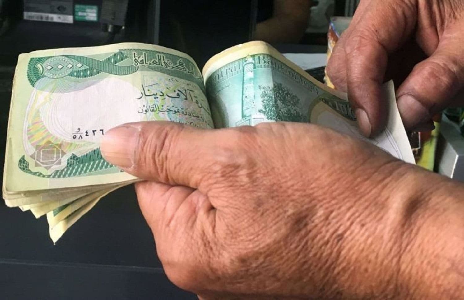A person counts a stack of 10,000 Iraqi dinars. File photo: AFP