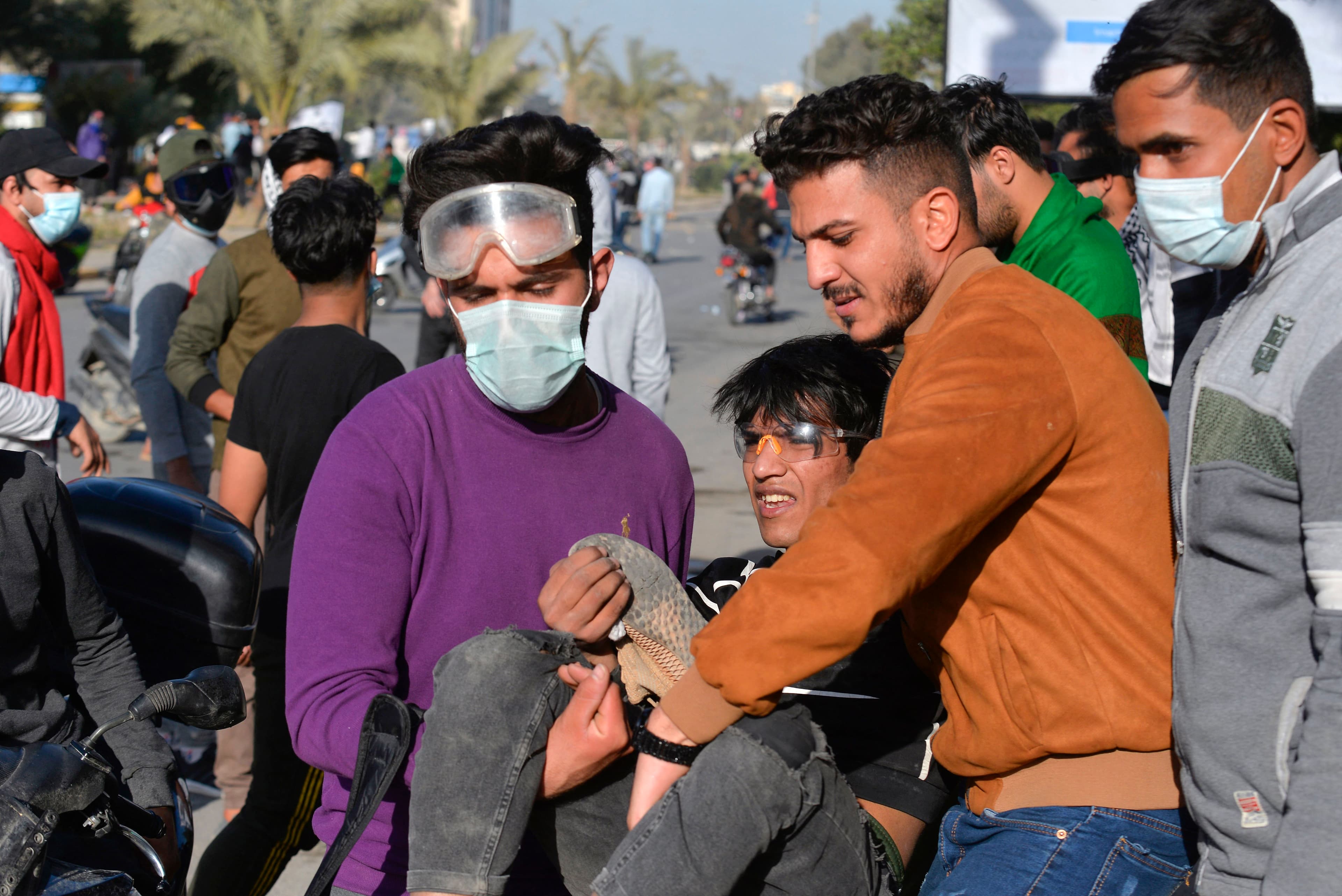 Iraqi anti-government protesters carry a wounded youth during a demonstration in the central Iraqi city of Najaf on March 14, 2021. Photo: Ali Najafi / AFP