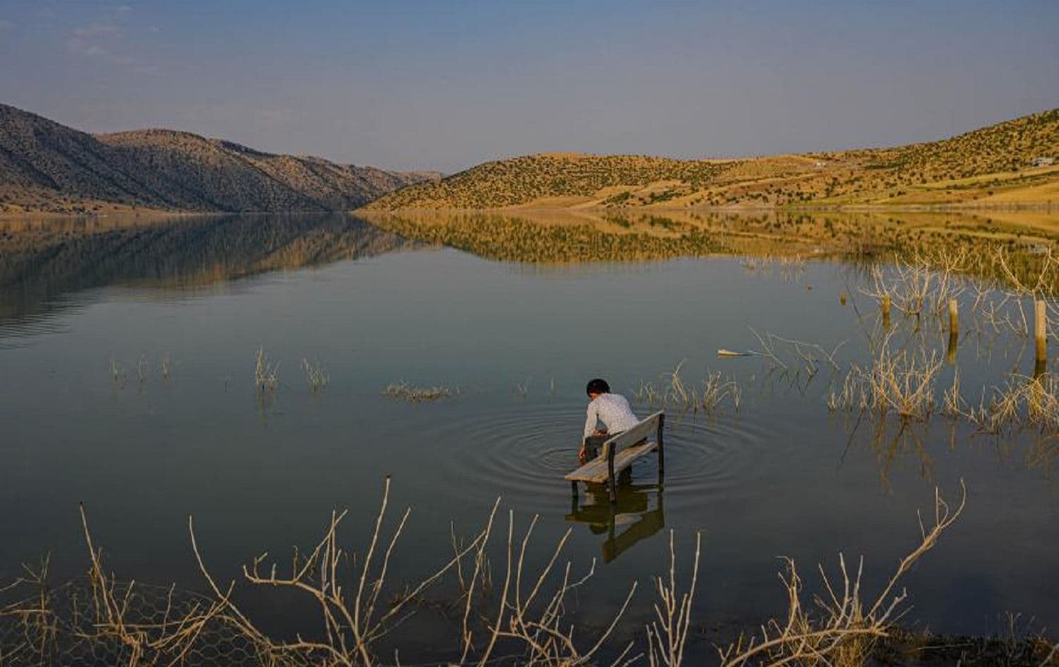 A boy sits on a school bench after his village and school were flooded by the Illisu Dam in Batman province on August 4, 2020. Photo: Bulent Killic/AFP 