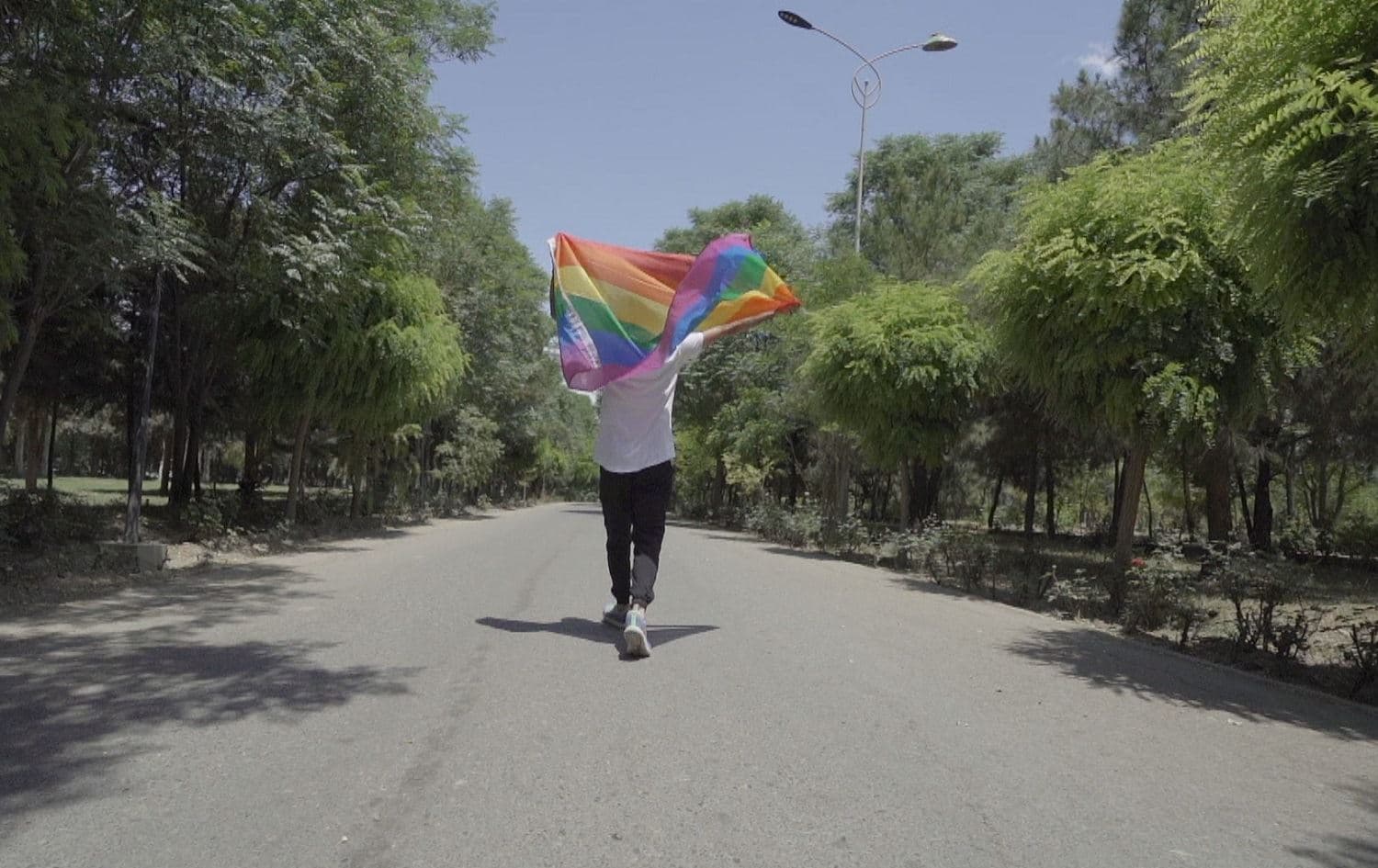A person runs through Erbil’s Sami Abdulrahman Park carrying a rainbow flag. Photo: Rudaw