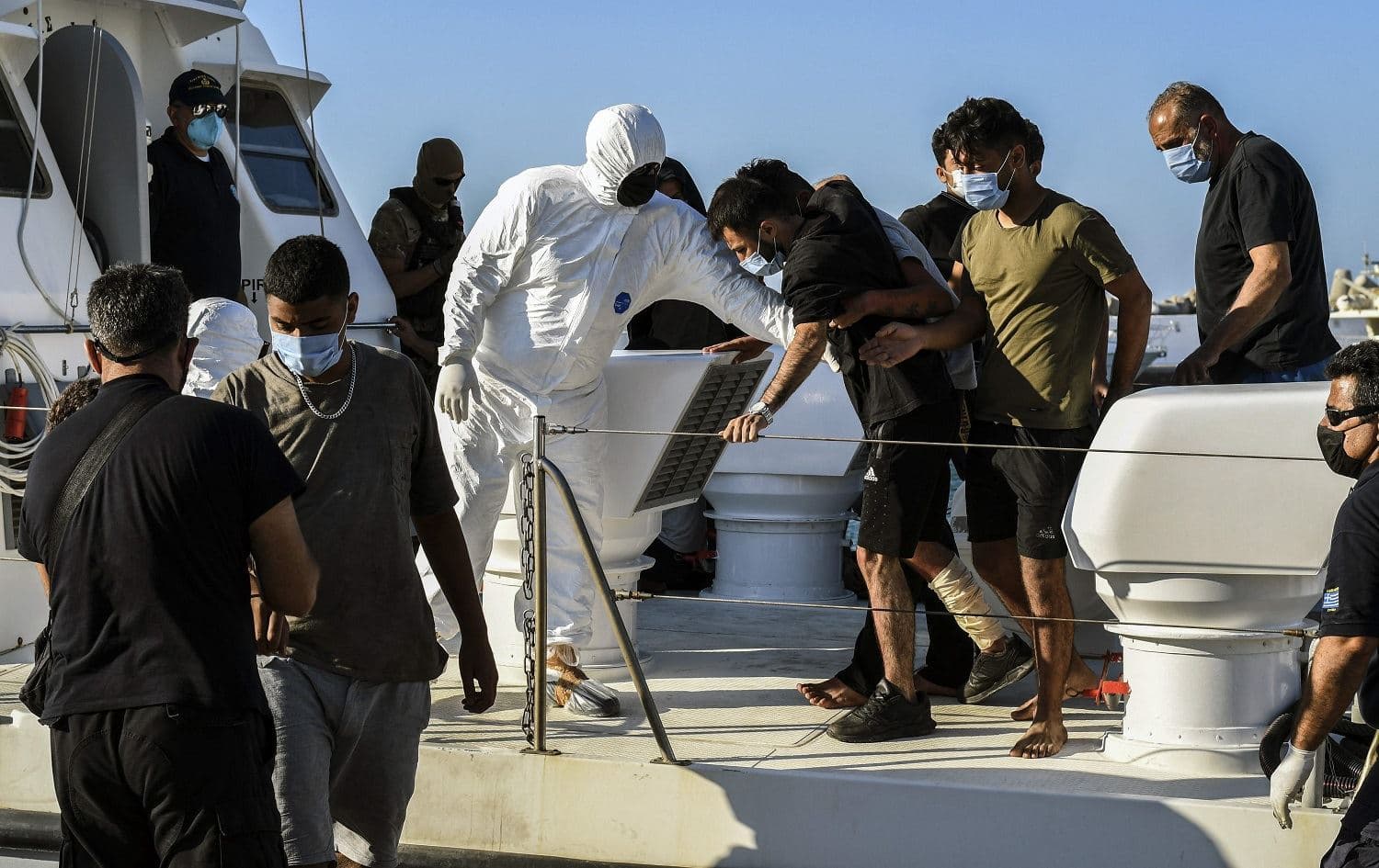 Rescued refugees and migrants disembark from a Greek coast guard vessel at the port of Ierapetra, on the island of Crete on July 23, 2021. Photo: Jason Tavlas/AFP