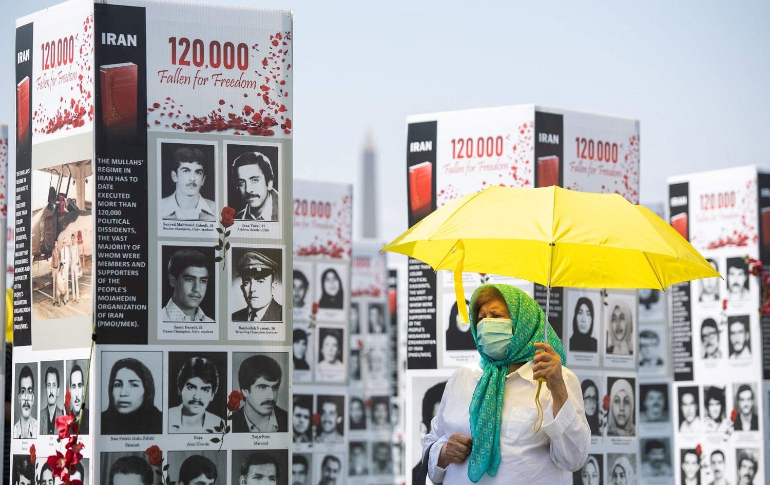 A woman with an umbrella walks past some of the thousands of photos of people killed in Iran during the 1988 massacre of political prisoners as well as during more recent anti-regime uprisings, during a photo exhibit in Washington, DC on September 4, 2020. File photo: Saul Loeb/AFP