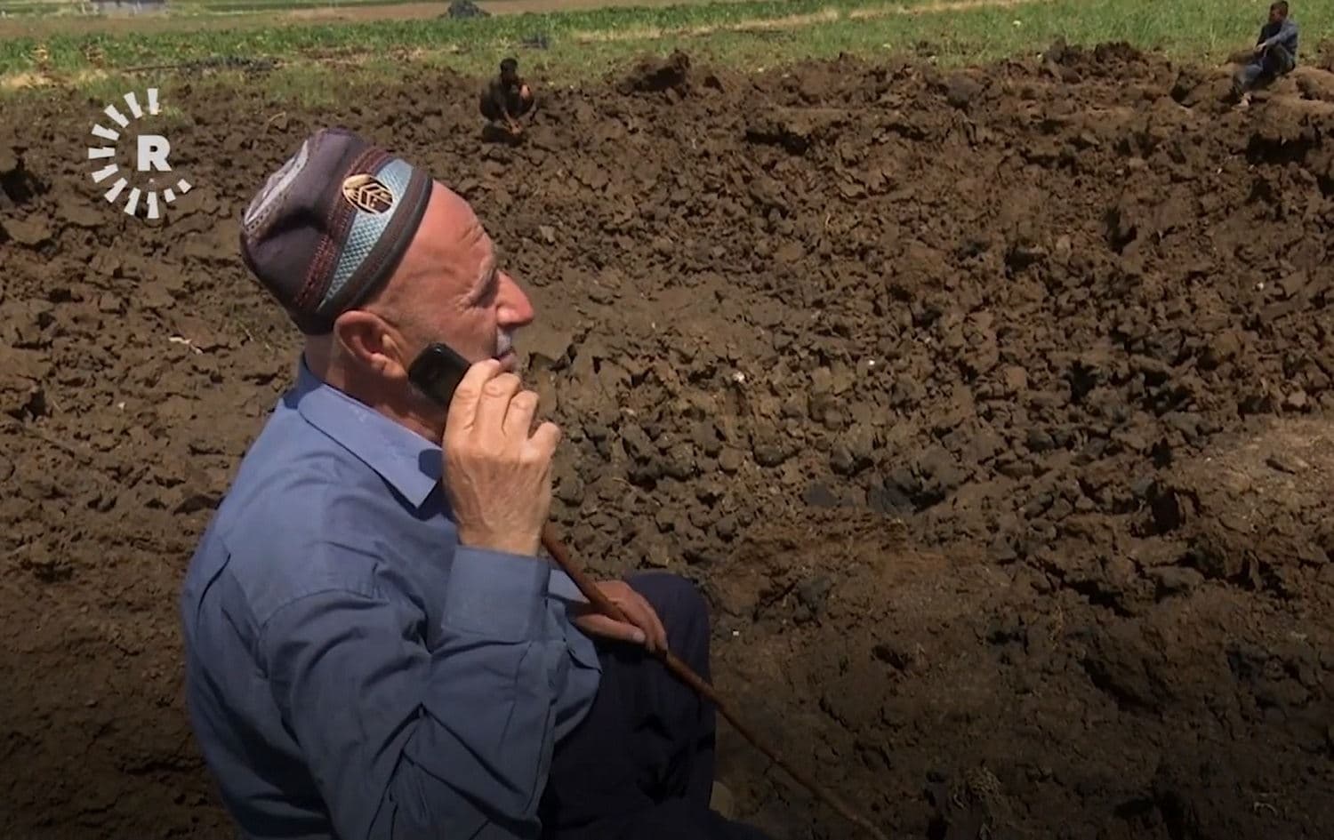 Farmer Karim Marif sits on the edge of a crater in his field, created by a Turkish bomb, in August 2021. Photo: Rudaw
