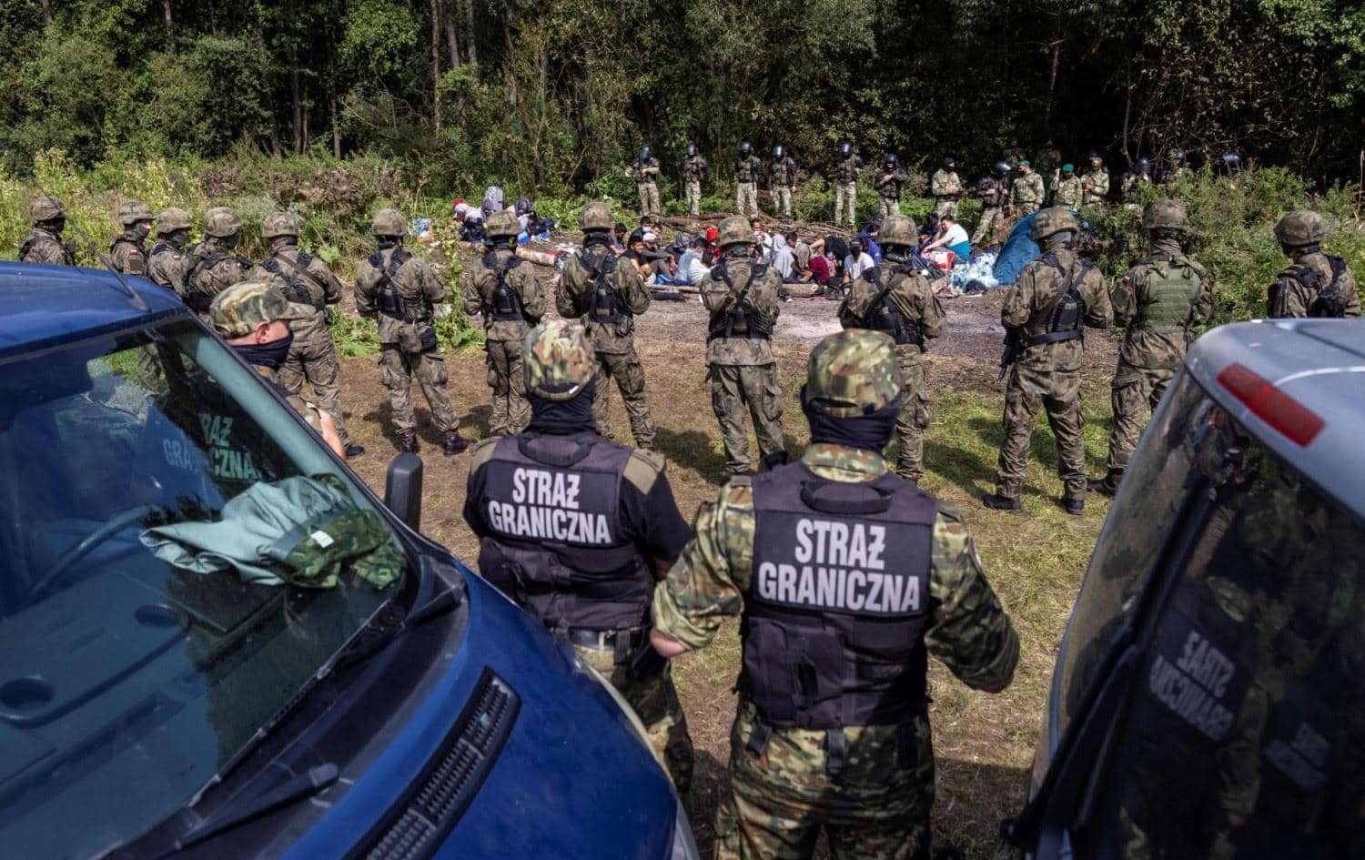 Polish border guards stand next to migrants, believed to be from Afghanistan, in the village of Usnarz Gorny, Poland, near the border with Belarus on August 20, 2021. Photo: Wojtek Radwanski/AFP 