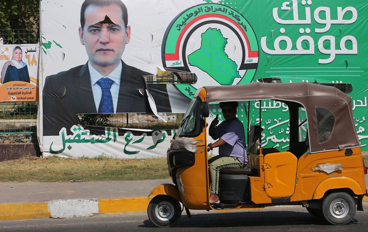 A tuk tuk drives past electoral billboards in Baghdad's Tahrir Square on October 4, 2021. Photo: Ahmad al-Rubaye/AFP